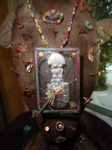 This detail symbolizes the shattering of the male side of the ego by a feminine consciousness. The gold object in the glass case is a small replica of the instrument used to sever the head in sacrificial prehispanic temple ceremonies. The hammer shattering the glass is meant to symbolize the gentling effect of the feminine on the msculine.
